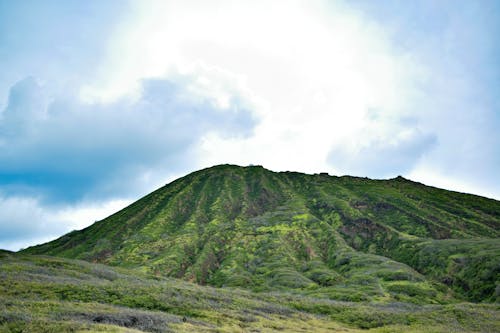 Scenic view of a verdant mountain under a cloudy sky in Waimea, Hawaii, perfect for nature enthusiasts.